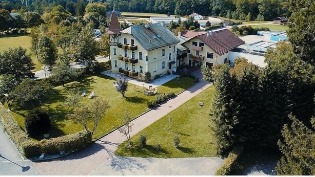 Ein großes, mehrstöckiges Gebäude im traditionellen Baustil, umgeben von üppiger Vegetation und Bergen im Hintergrund.