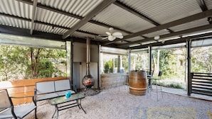 An outdoor patio with a metal roof, a fire pit, a wooden bench, and a table with chairs.