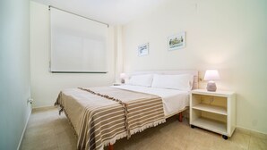 A hotel room with a bed, bedside tables, a lamp, and a whiteboard on the wall.
