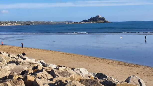 A beach with large rocks in the foreground, a small island with a building in the distance, and calm water. - Detached comfortable granite cottage, 5 minute walk to the beach - Dogs Welcome (Penzance)