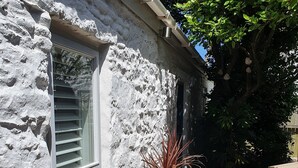 A rustic stone building with a window and a wooden planter box with plants. - Detached comfortable granite cottage, 5 minute walk to the beach - Dogs Welcome (Penzance)