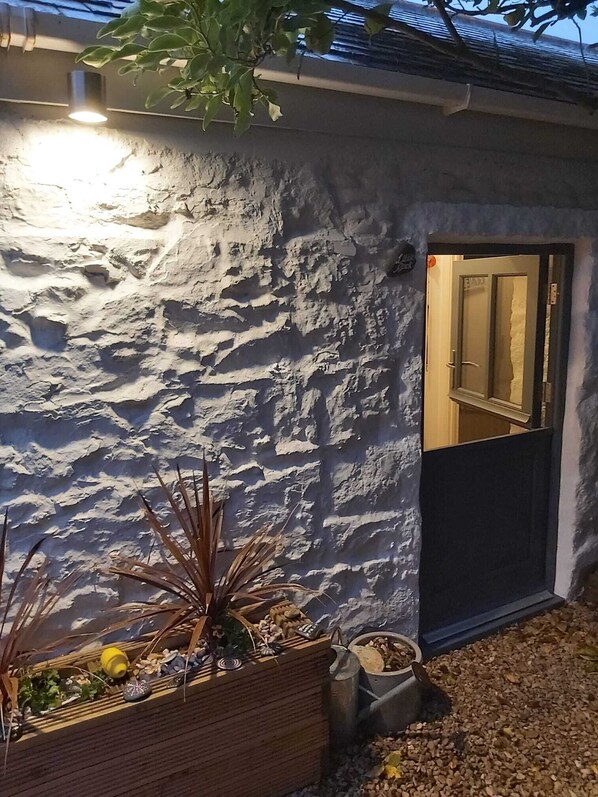 A rustic stone wall with a wooden planter box containing plants and decorative items.