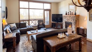 Una sala de estar con chimenea, televisor y muebles de cuero.