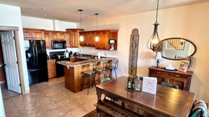 Una cocina moderna con armarios de madera, una isla central con taburetes de bar, microondas integrado y refrigerador.