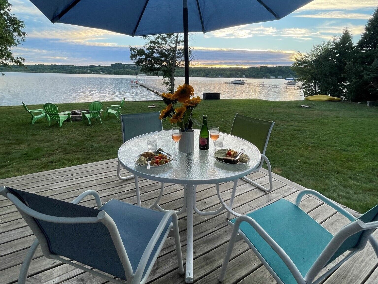 Un espace extérieur aménagé pour prendre les repas, avec une table, des chaises et une vue sur un lac.