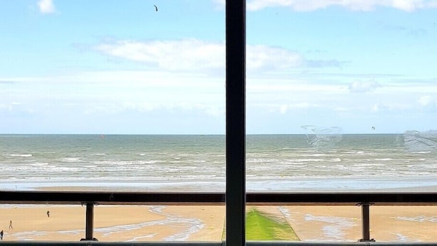 A view from a room with a large window overlooking a beach. There are two white plastic chairs in the foreground. - NEW !! Full sea view. Charming apartment 3 bedrooms private parking  (Cabourg)