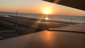 A sunset over a beach with a road and street lamps in the foreground. - NEW !! Full sea view. Charming apartment 3 bedrooms private parking  (Cabourg)