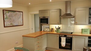 A kitchen with a microwave, oven, and a bread container.
