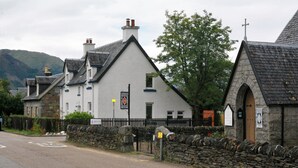 A traditional stone building with a white facade, a stone wall, and a sign indicating a no parking zone.