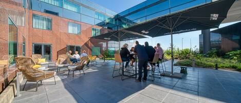 An outdoor seating area with modern furniture and a glass-roofed structure.