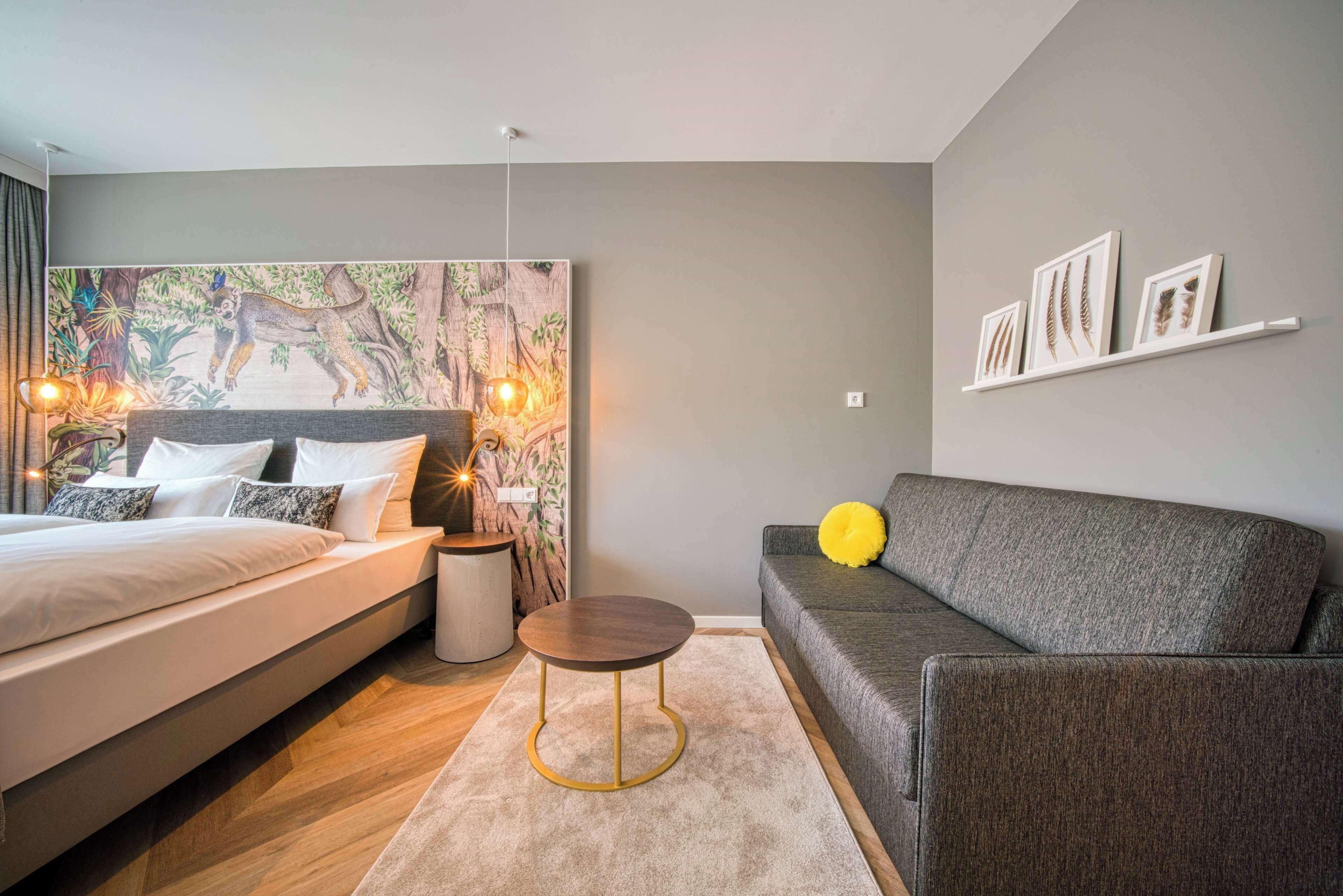 Un dormitorio moderno con cama, mesita de noche y sofá.