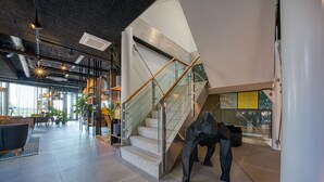 A modern interior with a staircase, glass railings, and contemporary furniture. - Vienna House Easy by Wyndham Amsterdam Airport (Hoofddorp)
