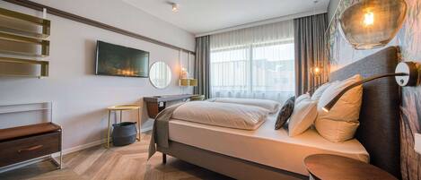 Une chambre d’hôtel moderne équipée d’un lit, d’une table de chevet, d’une lampe et d’une grande fenêtre avec des rideaux.