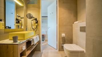 Un baño moderno con un lavabo amarillo, un espejo, un secador de pelo y un inodoro.
