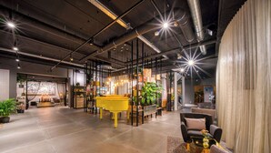 A spacious lobby with a piano, seating area, and plants. - Vienna House Easy by Wyndham Amsterdam Airport (Hoofddorp)