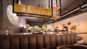 A bar area with a counter, seating, and a projection on the wall. - Vienna House Easy by Wyndham Amsterdam Airport (Hoofddorp)