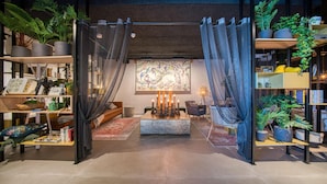 A modern interior with a central seating area, surrounded by shelves with plants and books. - Vienna House Easy by Wyndham Amsterdam Airport (Hoofddorp)