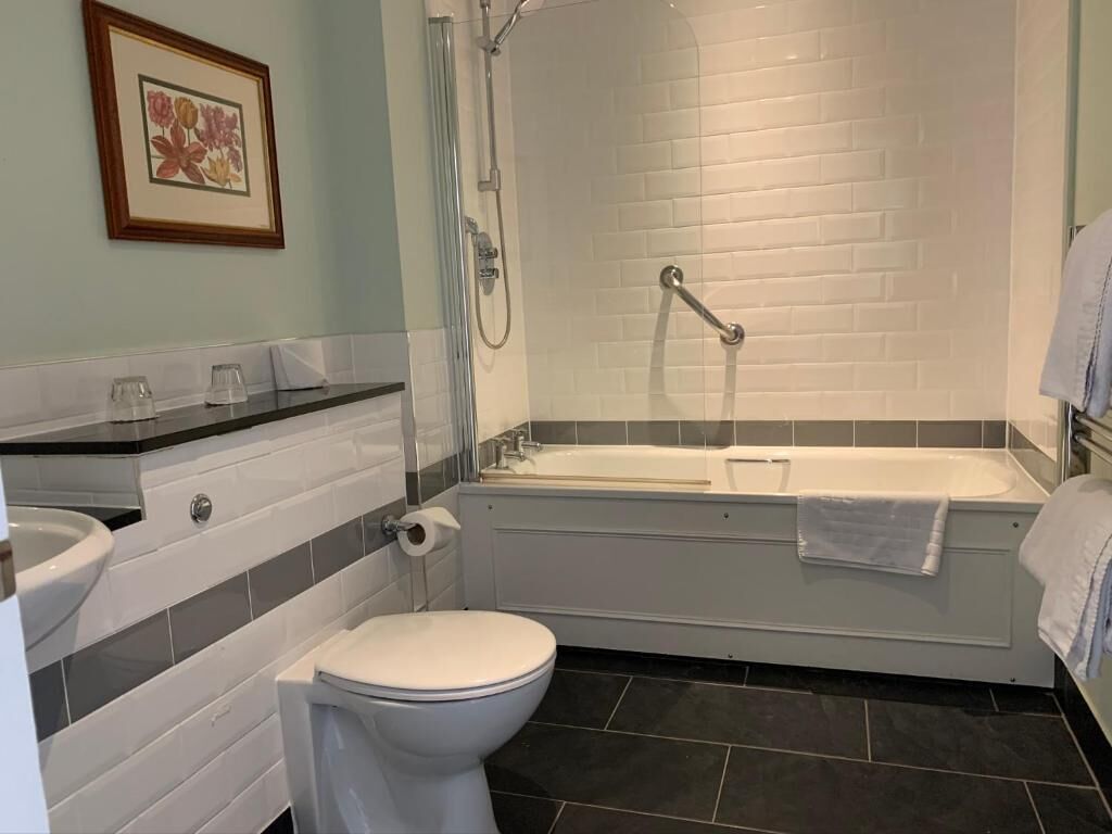 A bathroom with a toilet, sink, bathtub, and shower.