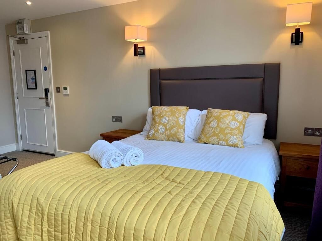 Ein Hotelzimmer mit einem Bett, zwei Nachttischen, einer Tür und zwei Wandlampen.