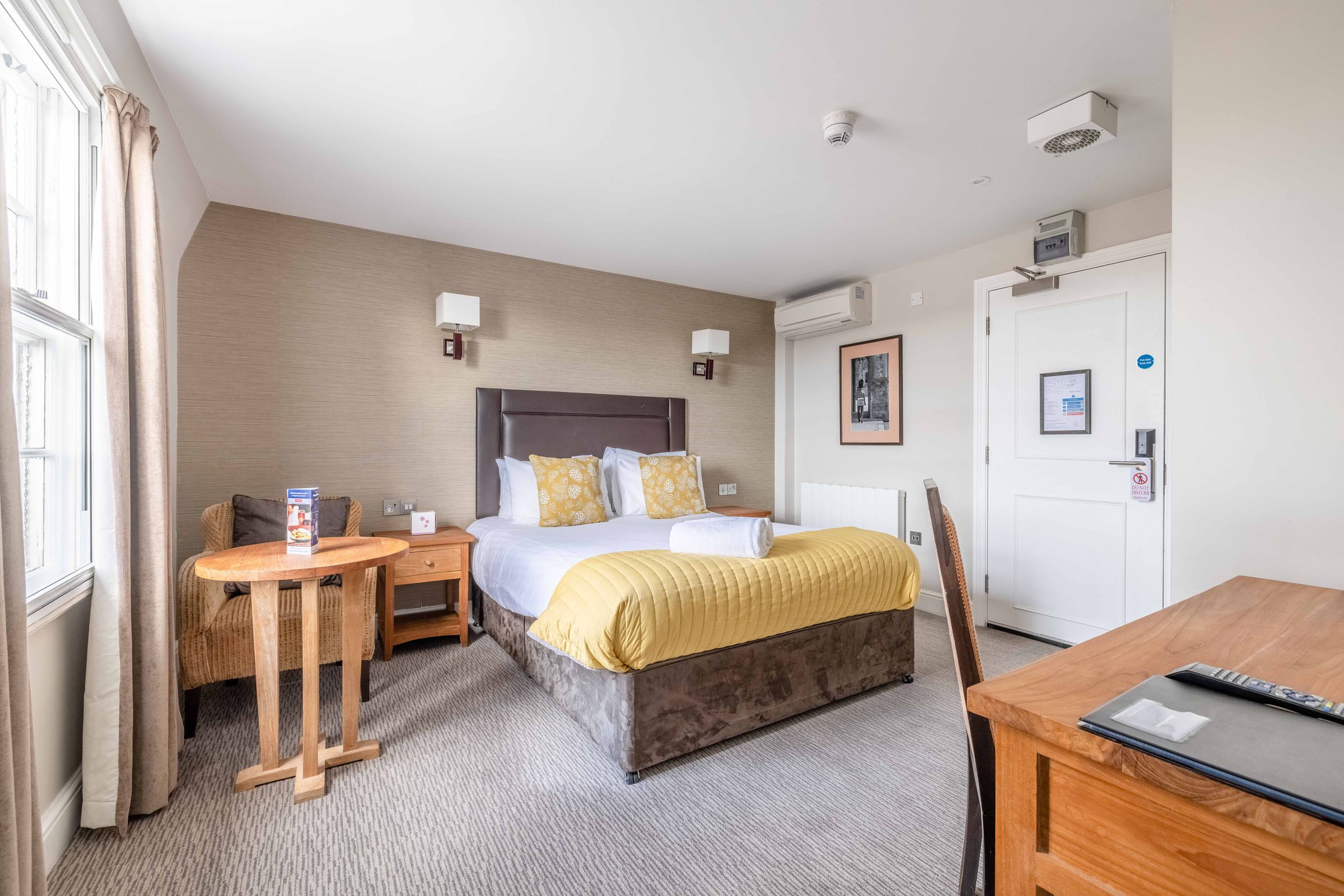 A hotel room with a bed, bedside tables, a desk, and a chair.