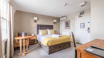 A hotel room with a bed, bedside tables, a desk, and a chair.