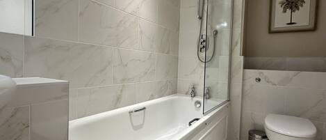 A modern bathroom with a freestanding bathtub, a toilet, and a shower area.
