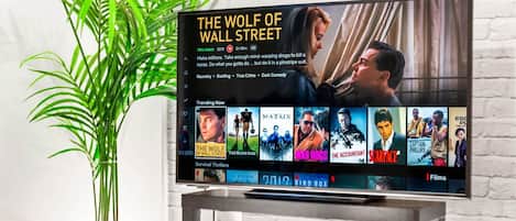 Un televisor mostrando 'The Wolf of Wall Street' y una planta a su lado.