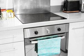 A kitchen with a stainless steel stove, oven, and a checkered towel hanging from the oven handle. - Stylish City Centre Apartment -  Terrace - Netflix (West Midlands)