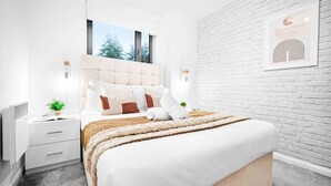 Una camera da letto moderna con un letto grande, pareti bianche, una parete decorata in mattoni e un'opera d'arte incorniciata sopra il letto.