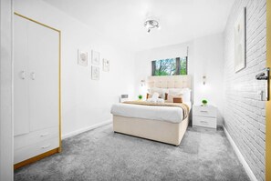 A modern bedroom with a large bed, bedside tables, a wardrobe, and a view of greenery through the window. - Stylish City Centre Apartment -  Terrace - Netflix (West Midlands)