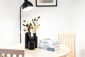 A round table with three books titled 'Vogue', 'Vogue', and 'Politics Today'. There are black vases with dried plants on the table.