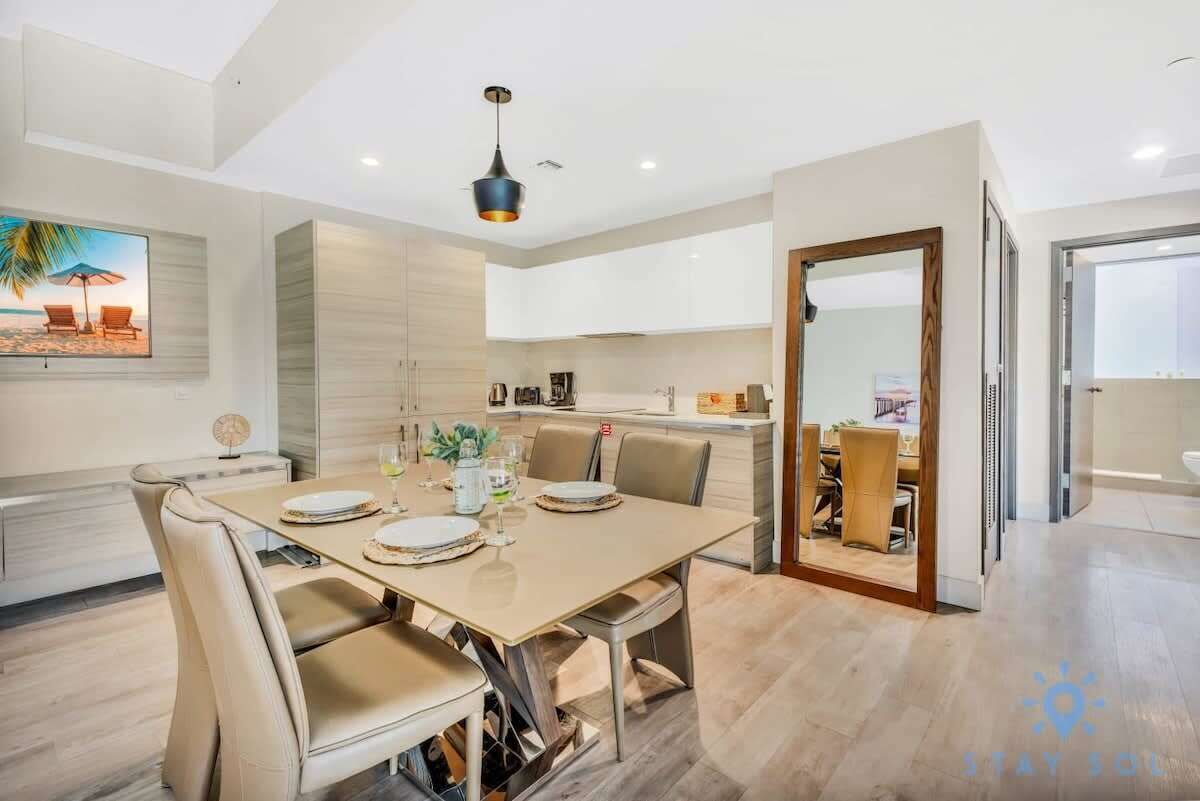 A modern dining area with a large table, chairs, and a pendant light.