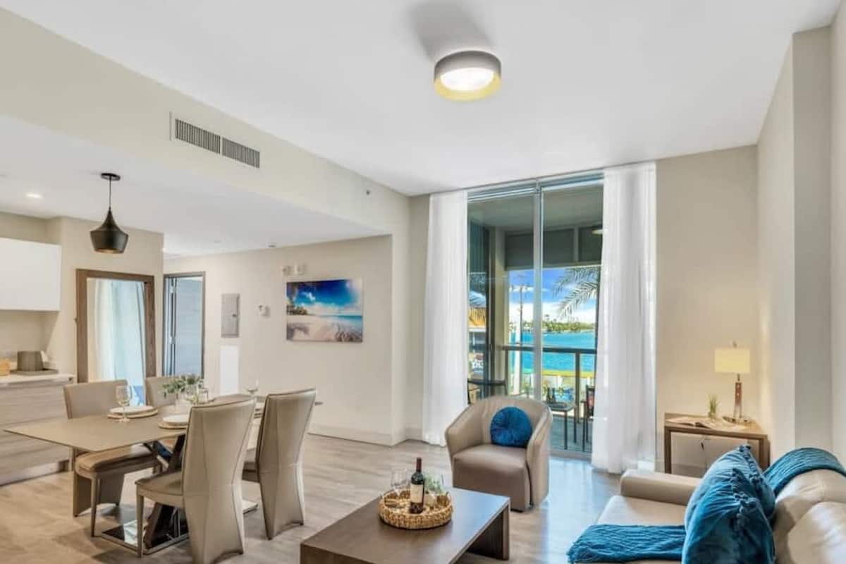 A modern living room with a sofa, coffee table, and a dining area with chairs and a table.