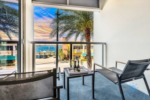 Un balcón con vista al mar, una palmera y una mesa con botellas.