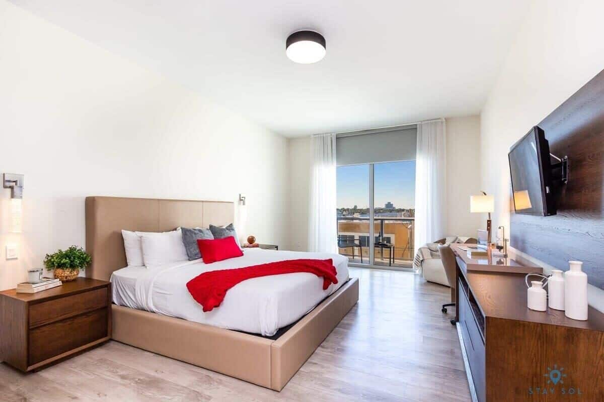 A modern hotel room with a large bed, a desk, and a TV.