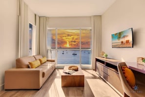 Una sala de estar moderna con un ventanal que ofrece vistas al mar y a barcos, un sofá, una mesa de centro y un comedor.