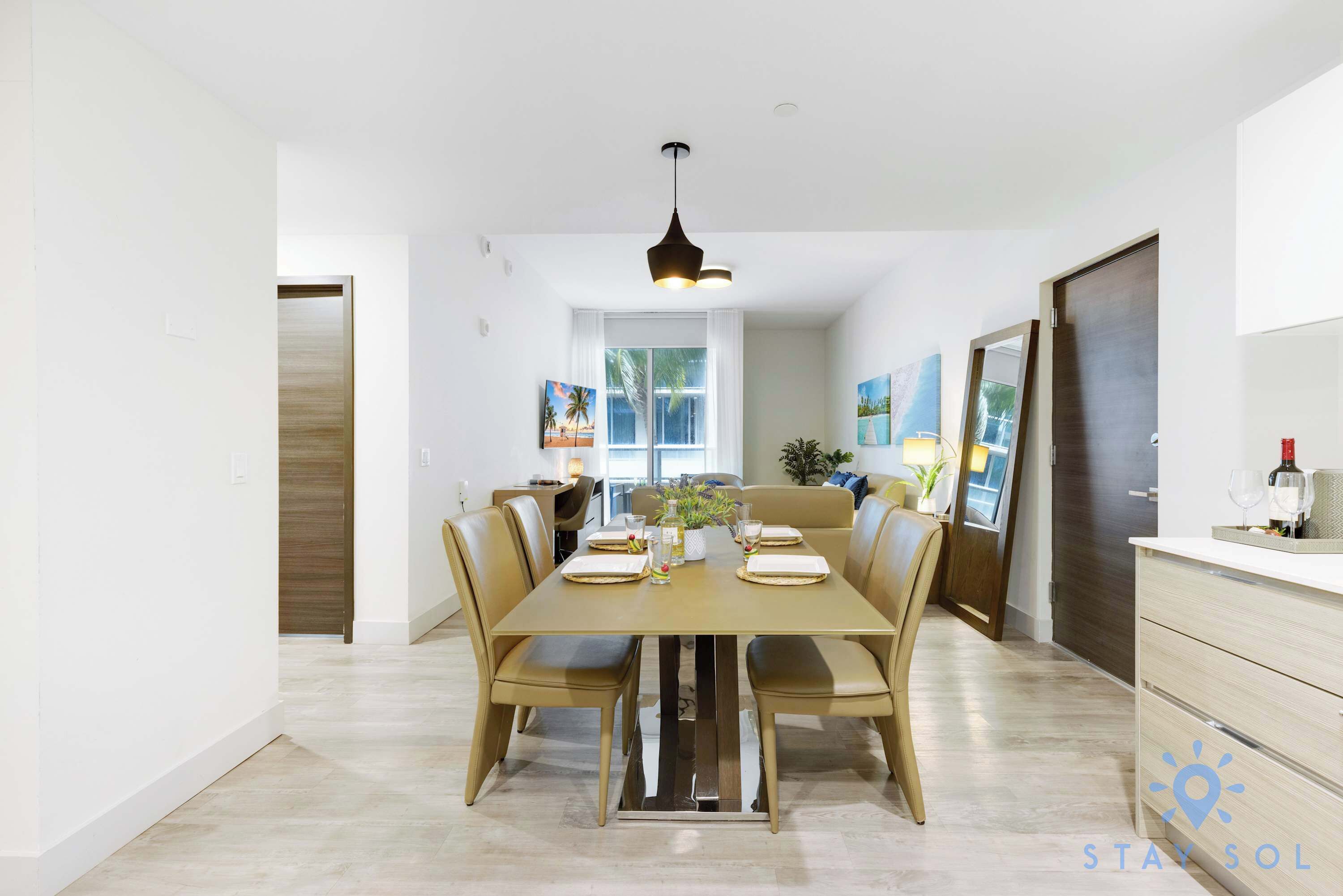 A dining area with a table set for four, a pendant light, and a view of the living room.