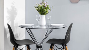 Ein moderner Esstisch mit zwei Stühlen, einer Blumenvase und zwei Weingläsern.