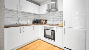 Una cucina moderna con mobili bianchi, una cappa in acciaio inossidabile, un forno integrato e un piano di lavoro in legno.