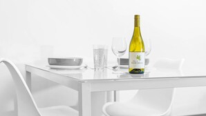 A modern dining table with a bottle of wine, two glasses, and a bowl. - Cutlass Suite - Broad Street - Parking (West Midlands)