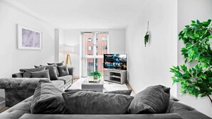 En moderne stue med en grå sofa, et fladskærms-tv og en plante.