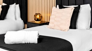 Una habitación de hotel con una cama bien hecha, una decoración en blanco y negro y una lámpara decorativa en la mesita de noche.