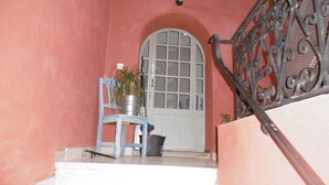 A staircase with a metal railing, a white door with glass panels, a blue chair, and a potted plant. - Classic France Double:AC, BBQ, fresh&clean, garden (Limoux)