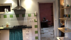 A kitchen with a gas stove, a stainless steel range hood, and a green and white tiled backsplash. - Classic France Double:AC, BBQ, fresh&clean, garden (Limoux)