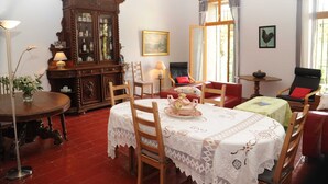 A dining area with a wooden table and chairs, a cabinet with glass doors, and a window with curtains. - Classic France Double:AC, BBQ, fresh&clean, garden (Limoux)