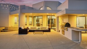 A modern outdoor living area with a sofa, coffee table, and barbecue grill. - Avila Beach Estate: Exceptional Hope Ranch (San Luis Obispo)