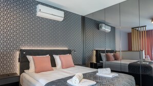 Een moderne hotelkamer met een wand met een geometrisch patroon, een groot bed met hoofdbord, nachtkastjes en een spiegel.