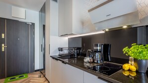 Een moderne keuken met een zwart aanrecht, roestvrijstalen apparatuur en een potplant.