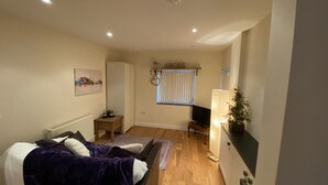 A bedroom with a bed, a desk, a chair, a radiator, a window with blinds, and a wall-mounted shelf with a plant. - Converted Stables - Pet Friendly - Enclosed Garden (Pontefract)