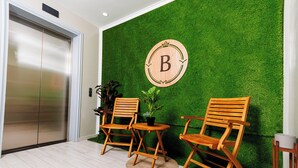 Une pièce avec un mur vert, une chaise en bois, une petite table et un ascenseur.
